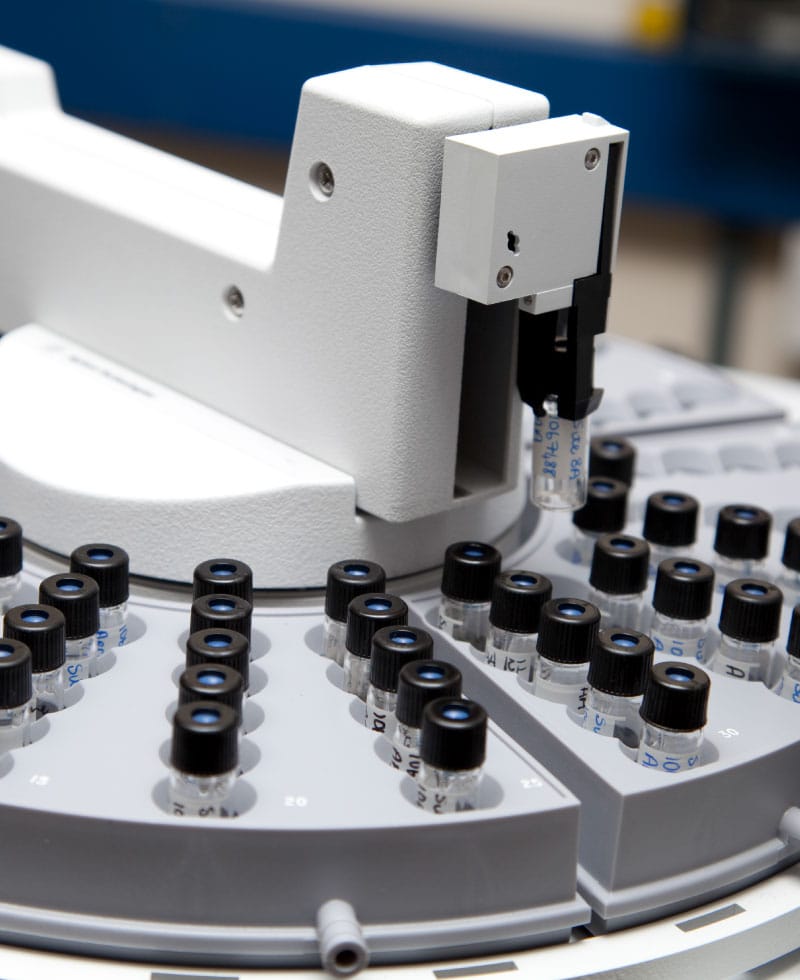 Close-up of gas chromatography analyzer with sample vials.
